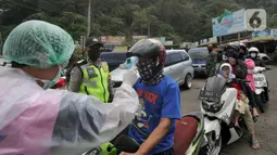 Petugas mengecek suhu tubuh pengendara saat penyekatan arus lalu lintas di Ciloto, Cianjur, Jawa Barat, Jumat (17/4/2020). Pemkab Cianjur melakukan pengecekan suhu tubuh dan penyemprotan disinfektan di titik keluar-masuk Cianjur untuk mencegah penyebaran COVID-19. (merdeka.com/Arie Basuki)