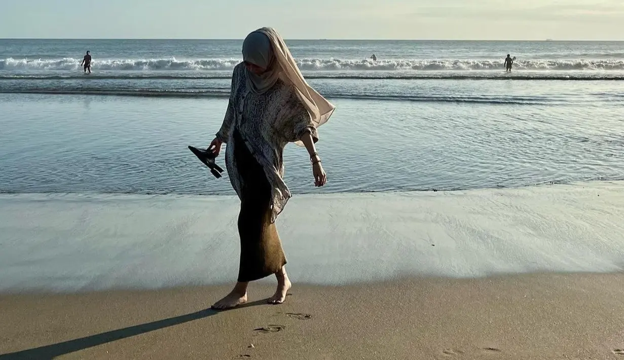 Bermain di pantai, Adiba terlihat syari dan feminin. Dia tampil mengenakan tunik bermotif dengan skirt yang membuatnya terliha anggun dan adem
