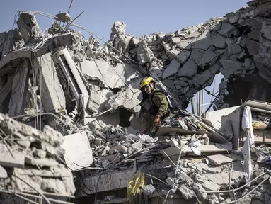 Petugas tanggap darurat Israel memeriksa sebuah lokasi yang terkena rudal yang ditembakkan dari Iran di selatan Tel Aviv pada 14 Juni 2025. (JOHN WESSELS/AFP)