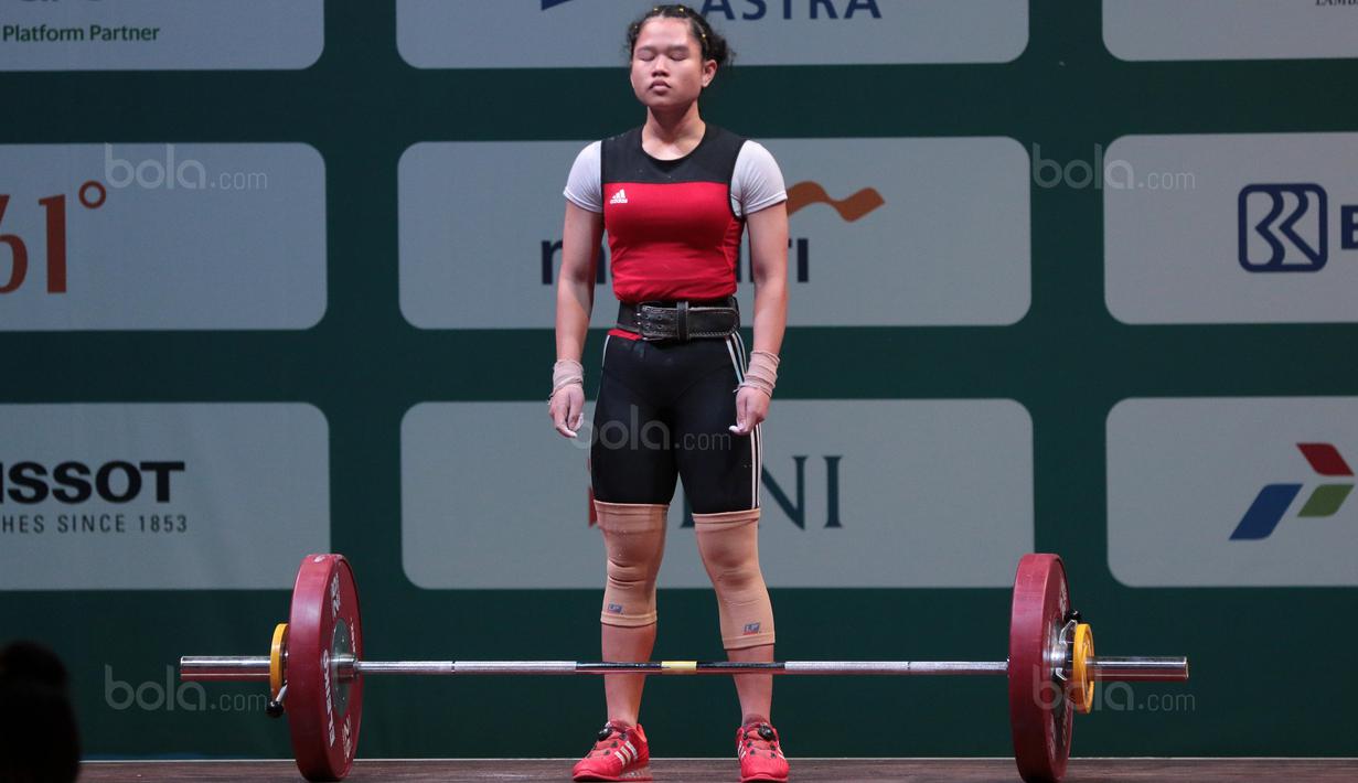 Yolanda Putri menenangkan diri sebelum mengangkat beban saat turun pada kelas 48 kg di Hall A Arena PRJ, Jakarta, Rabu (11/2/2018). Yolanda Putri berhasil meraih medali perunggu dengan total angkatan 158. (Bola.com/Nicklas Hanoatubun)