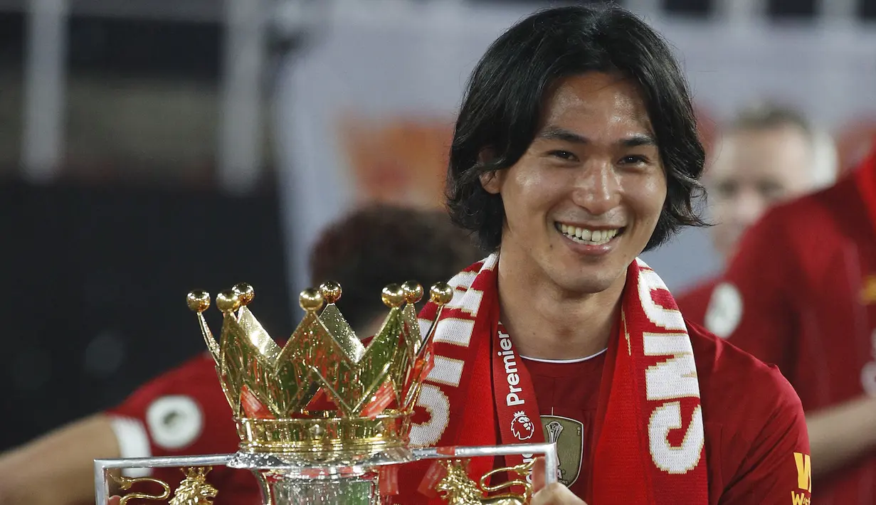 Selebrasi gelandang Liverpool, Takumi Minamino dengan trofi juara Liga Inggris 2019/2020 setelah laga menghadapi Chelsea di Anfield Stadium, Liverpool (22/7/2020). Takumi Minamino menjuarai Liga Inggris bersama Liverpool pada musim 2019/2020. Takumi Minamino diboyong langsung Liverpool dari RB Salzburg pada tengah musim 2019/2020. Pada awal musim 2022/2023 Liverpool melepasnya ke AS Monaco setelah sempat dipinjamkan ke Southampton. (AFP/Pool/Phil Noble)