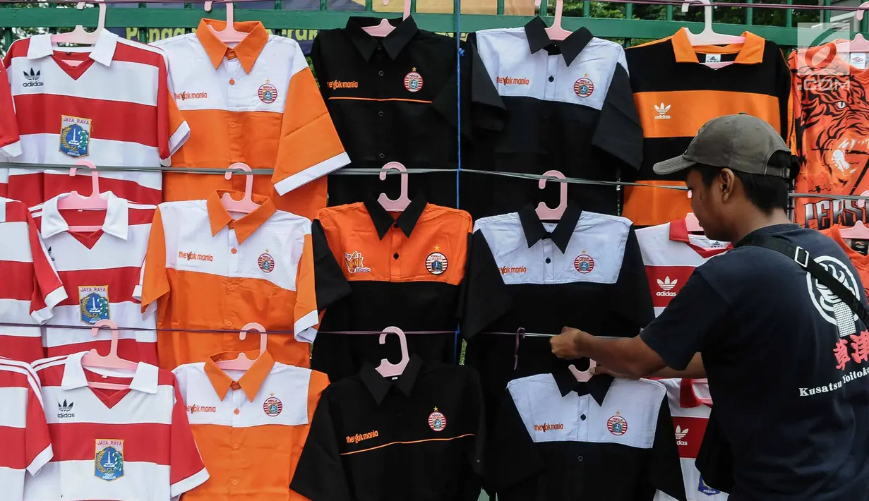 Pedagang merapikan kaos Persija di kawasan Senayan, Jakarta, Minggu (9/12). Pedagang menjual aksesoris dan atribut Persija seperti baju, bendera, dan syal dengan kisaran harga Rp.50.000 - Rp. 100.000. (Liputan6.com/Faizal Fanani)