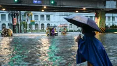Orang-orang berjalan di sepanjang jalan yang tergenang banjir di Manila, Filipina pada 24 Juli 2024 di tengah hujan deras yang dibawa oleh Topan Gaemi. (Jam Sta Rosa/AFP)