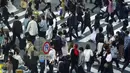 Orang-orang yang mengenakan masker pelindung untuk membantu mengekang penyebaran virus corona COVID-19 menyeberang jalan di Distrik Shibuya, Tokyo, Jepang, Rabu (7/4/2021). Tokyo mengonfirmasi lebih dari 550 kasus COVID-19 baru pada 7 April 2021. (AP Photo/Eugene Hoshiko)