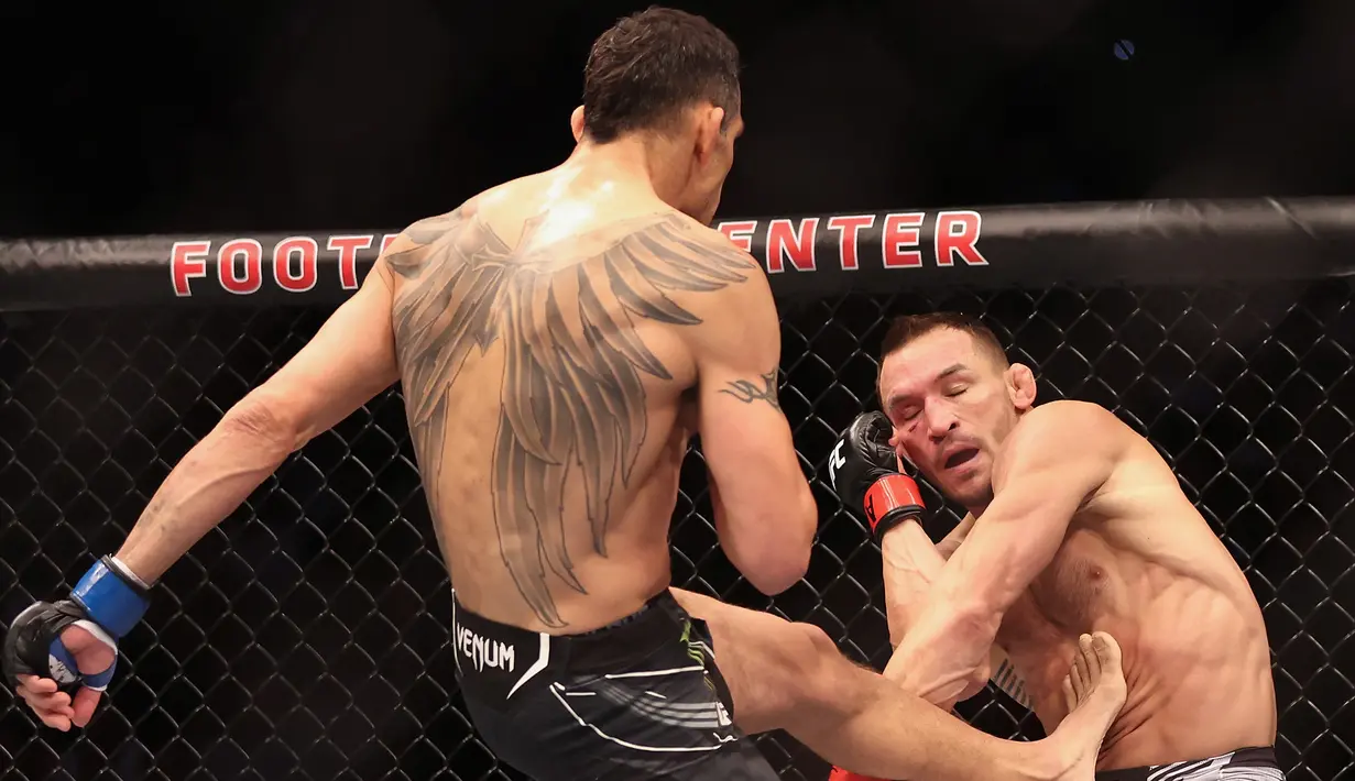 <p>Tony Ferguson (kiri) menendang Michael Chandler pada pertarungan kelas ringan putra UFC 274 di Footprint Center, Phoenix, Arizona, Amerika Serikat, 7 Mei 2022. Chandler dinyatakan menang KO atas Ferguson. (Christian Petersen/Getty Images/AFP)</p>