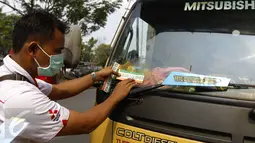 Petugas menempelkan stiker tanda lulus uji emisi di kendaraan usai melakukan pengujian kendaraan, Depok, Rabu (4/11/2015).Kemeterian Lingkungan Hidup dan Kehutanan RI gelar uji emisi kendaraan roda empat secara gratis di Depok. (Liputan6.com/Yoppy Renato)