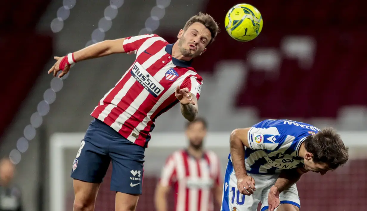 Gelandang Atletico Madrid, Saul Niguez (kiri) menyundul bola di atas gelandang Real Sociedad, Mikel Oyarzabal dalam laga lanjutan Liga Spanyol 2020/2021 pekan ke-36 di Wanda Metropolitano Stadium, Rabu (12/5/2021). Atletico menang 2-1 atas Sociedad. (AP/Bernat Armangue)