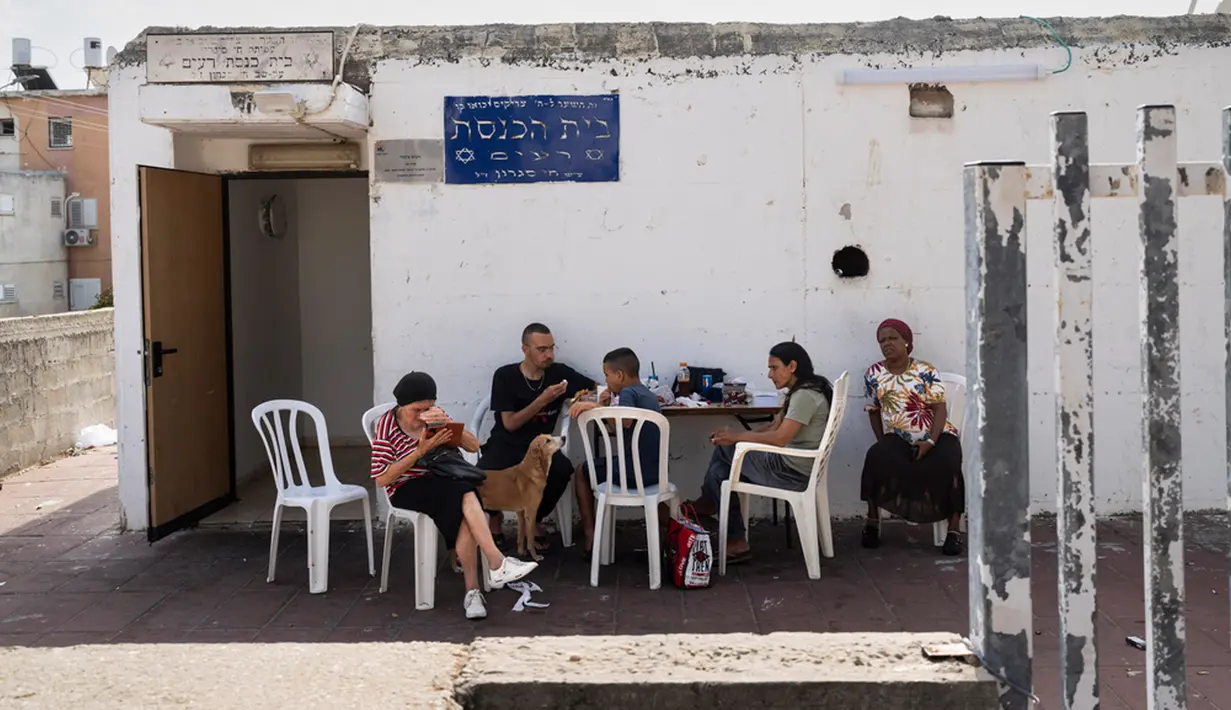 Warga makan siang di luar lingkungan tempat perlindungan bom atau shelter di Ashkelon, Israel, Selasa (31/10/2023). Warga Israel memanfaatkan tempat perlindungan darurat di rumah dan ruang publik ketika perang antara Israel dan kelompok militan Hamas meningkat. (AP Photo/Bernat Armangue)