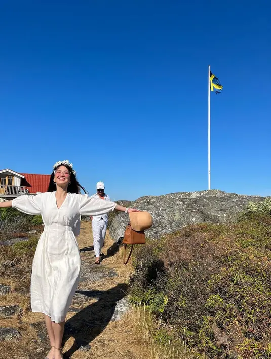 Raline Shah tampil menawan mengenakan gaun midi warna putih berkerah v-neck yang jadi ciri khas festival tersebut. Dipermanis dengan mahkota bunga yang ia buat sendiri. [Foto: IG/ralineshah].