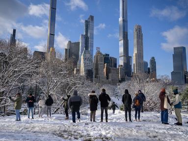 Orang-orang berdiri di viewpoint Central Park setelah badai salju pertama musim dingin 2022 di New York City, Jumat (7/1/2022). Badai musim dingin membawa lebih dari 15 cm salju di bagian timur Amerika Serikat (AS), menutup sekolah, kantor dan jalan-jalan. (Ed JONES / AFP)