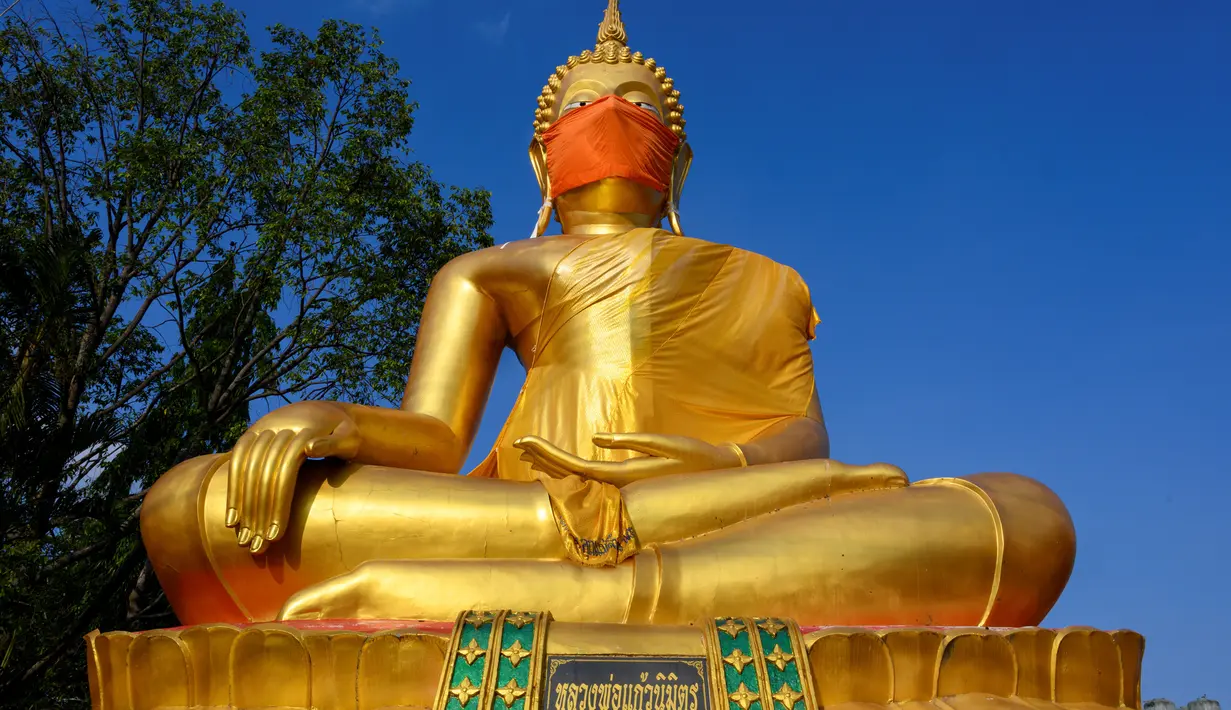 Masker diletakkan pada wajah patung Buddha raksasa di kuil Wat Nithet Rat Pradit di Pathum Thani di luar Bangkok, Thailand, 12 Mei 2020. Pemasangan masker tersebut sebagai tanggapan terhadap penyebaran pandemi Covid-19. (Photo by Mladen ANTONOV / AFP)