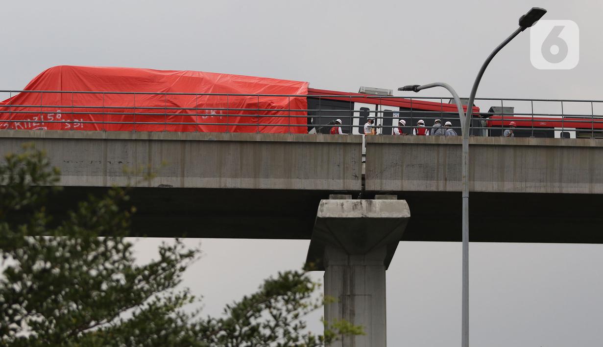 Petugas mengecek kereta ringan lintas rel terpadu (LRT) Jabodebek yang mengalami kecelakaan di jalur lintas LRT Cibubur, Jakarta Timur, Senin (25/10/2021). Petugas terlihat ada di rel untuk membantu proses evakuasi di mana bagian gerbong kereta ditutup terpal. (Liputan6.com/Herman Zakharia)