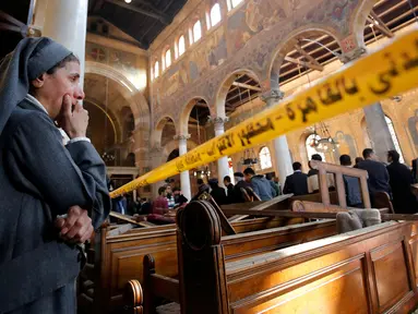 Seorang biarawati menangis sambil berdiri mengamati kondisi Gereja Katedral Koptik di Kairo, Mesir, Minggu (11/12). Ledakan yang menghantam gereja tersebut menewaskan sedikitnya 25 orang dan melukai 49 lainnya. (REUTERS/Amr Abdallah Dalsh)