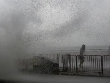 Warga berlari ketika ombak besar menghantam pesisir Hong Kong menyusul terjangan Topan Haima, Tiongkok, Jumat (21/10). Sebelum tiba di Hongkong, topan Haima terlebih dulu menerjang Filipina. (REUTERS/Bobby Yip) 