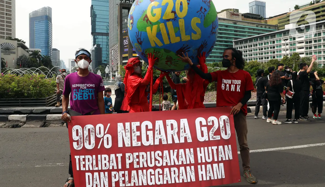 Aktivis iklim melakukan teatrikal dengan membawa bola dunia saat aksi di kawasan Bundaran Hotel Indonesia, Jakarta, Minggu (13/11/2022). Aksi yang digelar berbarengan dengan penyelenggaraan G20 ini meminta pemimpin dunia menemukan solusi bersama atas kondisi ekonomi global. (Liputan6.com/Herman Zakharia)