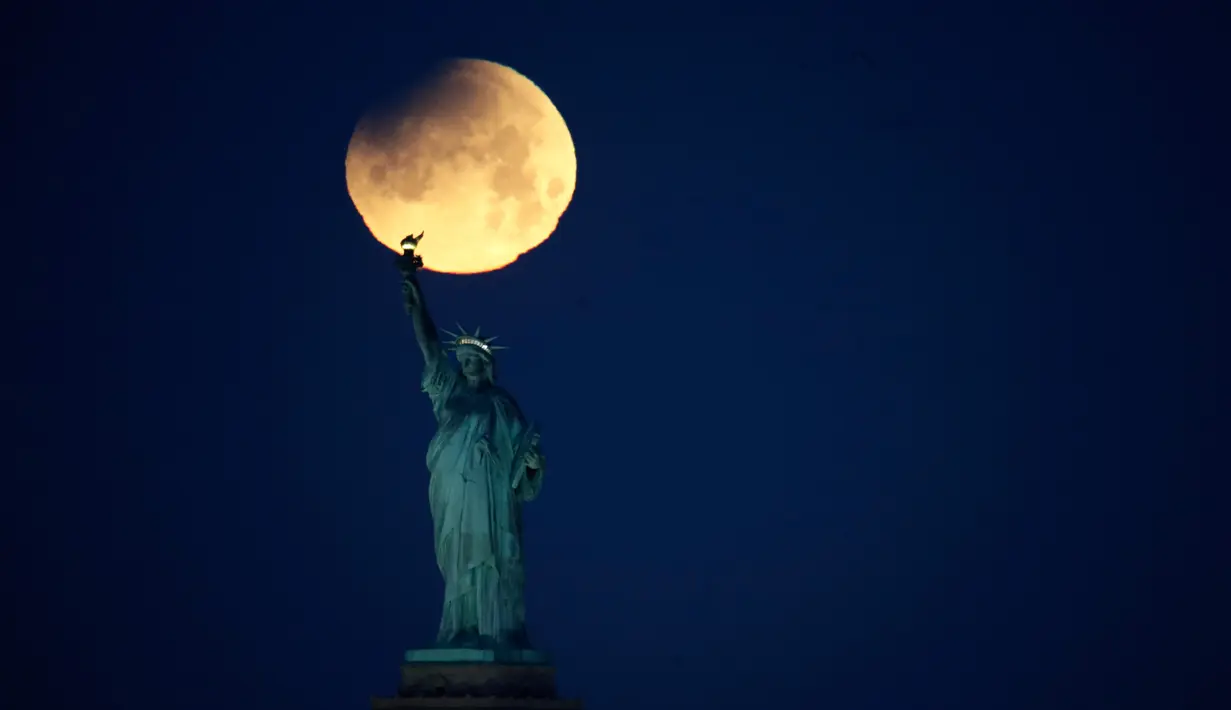 Pemandangan ketika Patung Liberty dihiasi oleh supermoon di Brooklyn, New York, Amerika Serikat, Rabu (31/1). (AP Photo/Julio Cortez)