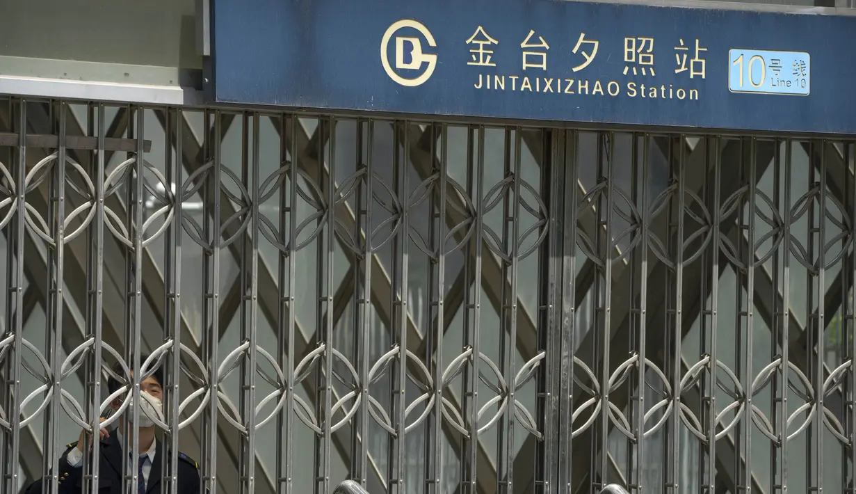 <p>Seorang pekerja yang mengenakan masker berdiri di dalam gerbang pintu keluar stasiun kereta bawah tanah yang tertutup di Beijing, China Rabu (4/5/2022). Beijing pada hari Rabu ini menutup lebih dari 40 stasiun kereta bawah tanah, sekitar sepersepuluh dari jaringan kereta, sebagai bagian dari tindakan untuk menghentikan penyebaran Covid-19. (AP Photo/Mark Schiefelbein)</p>