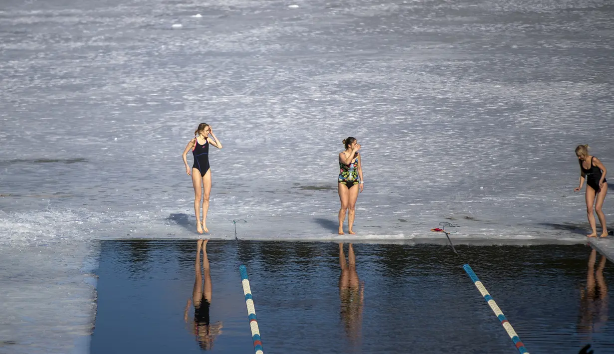 Para perenang bersiap bertanding dalam kompetisi renang musim dingin di lubang es sepanjang 25 meter di danau dekat Vilnius, Lithuania, Sabtu (6/3/2021).  Suhu air saat itu 3 derajat Celcius, sedangkan udaranya -3 derajat Celsius. (AP Photo/Mindaugas Kulbis)
