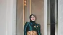 Aurel Hermansyah kenakan kebaya janggan berwarna biru teal yang memukau dan tampak mewah. Dipadukan dengan corset batik yang dihiasi aksen ekor panjang menjuntai, kesan anggun dan glamor semakin terpancar dari keseluruhan penampilannya.  [@aurelie.hermansyah].