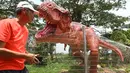 Seorang pria berjalan melewati model dinosaurus seukuran aslinya, Tyrannosaurus Rex ditampilkan di sepanjang "Changi Jurassic Mile" jalan santai di Singapura (13/10/2020). (AFP/Roslan Rahman)