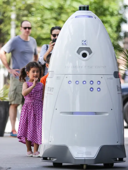 Dua orang anak berinteraksi dengan robot ROD2 di River Oaks District, Houston (18/8). Robot kemananan ini dirancang oleh Knightscope yang berbasis Silicon Valley. (Michael Ciaglo / Houston Chronicle via AP)