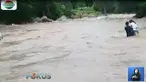 Warga terpaksa menggotong motor menyeberangi sungai karena tidak adanya jembatan di sungai tersebut.