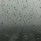 Tetesan air hujan yang ada di jendela kaca dengan latar belakang mendung menyelimuti langit Jakarta, Kamis (1/2). BMKG juga meminta warga mengantisipasi potensi angin berkecepatan tinggi. (Liputan6.com/Immanuel Antonius)