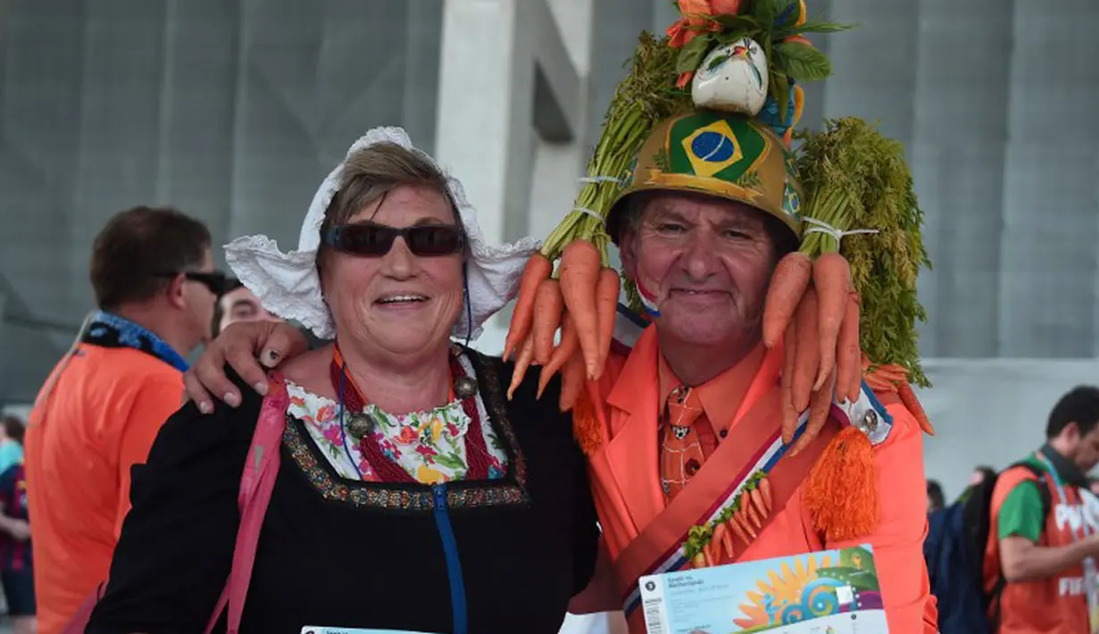 Dengan berpakaian ala petani, sepasang suporter Belanda bersiap menyaksikan laga perdana Grup B Piala Dunia 2014 di Fonte Nova Arena, Salvador, Brasil, (14/6/2014). (AFP PHOTO/Damien Meyer)
