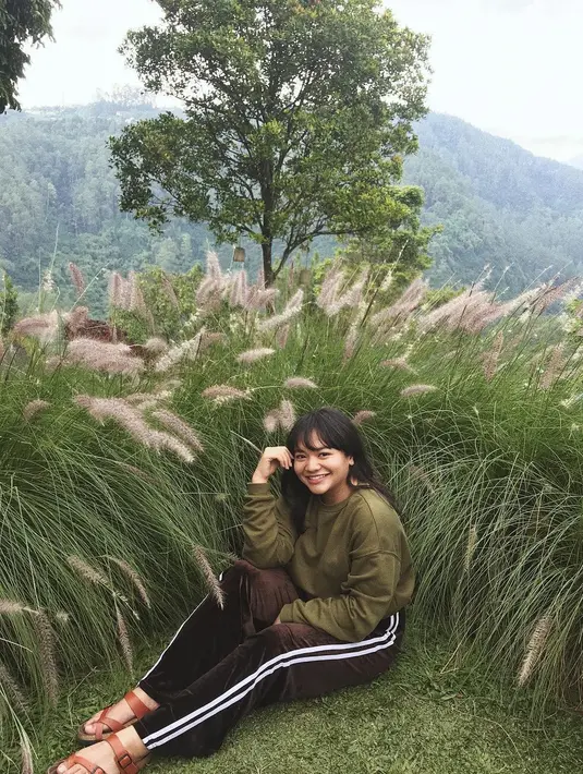 Selain girly, artis cilik yang kini sudah duduk di bangku SMA ini juga kerap berpenampilan sporty. Duduk di hamparan rumput, Amel memakai celaa training dan atasan kaus lengan panjang warna hijau lumut.  (Instagram/amelcarla)