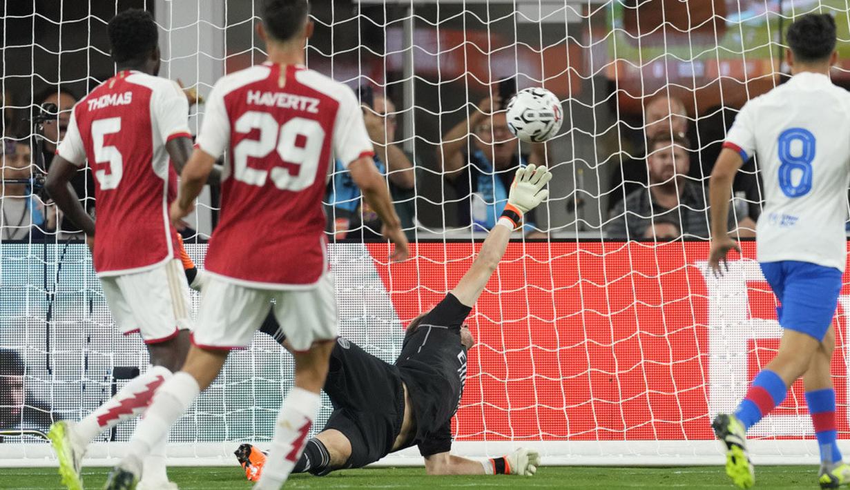 Kiper Arsenal, Aaron Ramsdale, gagal menghalau bola tendangan pemain Barcelona, Robert Lewandowski, dalam laga pramusim di Stadion SoFi, Inglewood, California, Kamis (27/7/2023). Arsenal menang dengan skor 5-3 atas Barcelona. (AP Photo/Ashley Landis)