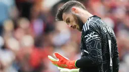 Kiper Manchester United, David de Gea, mengamati kedua tangannya saat melawan Brighton and Hove Albion pada laga Liga Inggris di Stadion Old Trafford, Minggu (07/08/2022). (AP/Lindsey Parnaby)