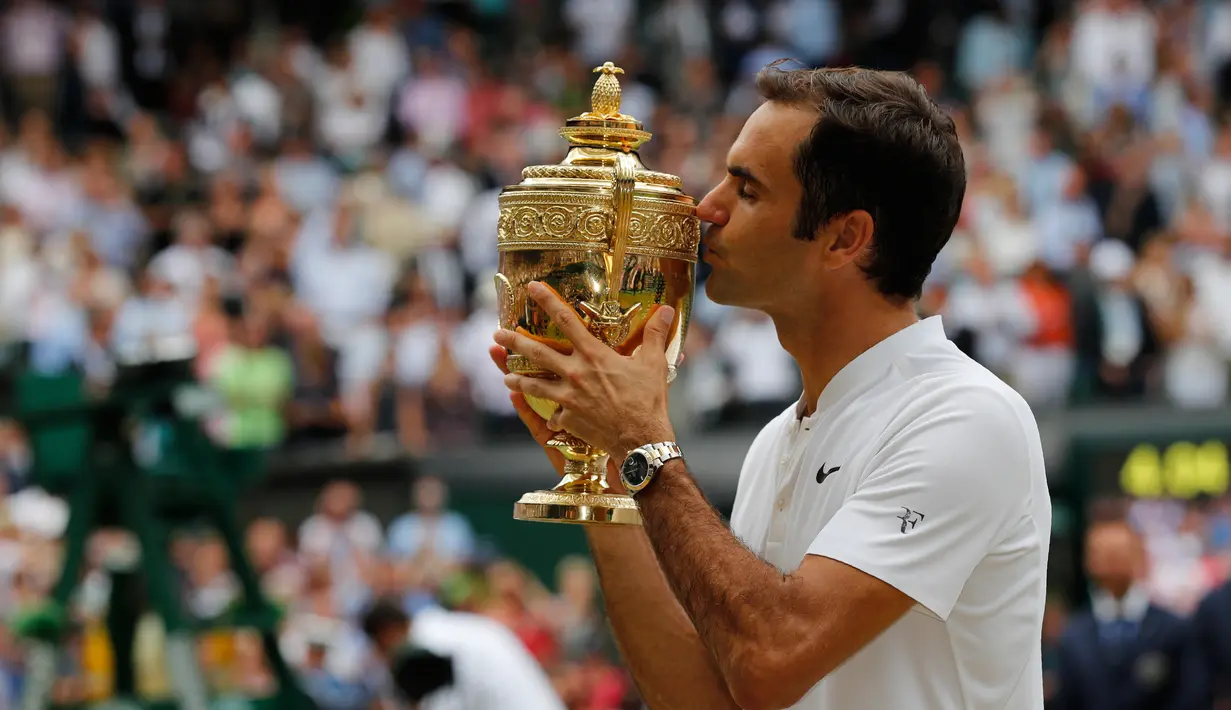Petenis Swiss, Roger Federer mencium trofi setelah melawan petenis Kroasia, Marin Cilic pada pertandingan final tunggal putra Kejuaraan Wimbledon 2017 di Wimbledon, London. (16/07). Roger Federer menang 6-3, 6-1, 6-4. (AFP Photo / Adrian Dennis)