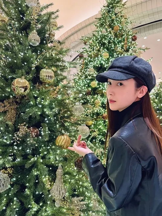 Jessica Jung berfoto dengan pohon Natal dihiasi ornamen gold. Ia tampil serba hitam dengan topi dan jaket leathernya. [@jessica.syj]