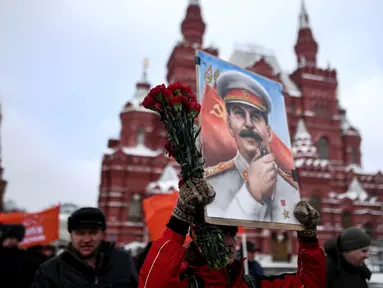 Seorang wanita membawa lukisan potret Stalin saat menghadiri upacara memperingati 65 tahun kematian pemimpin Uni Soviet Joseph Stalin di Lapangan Merah, Moskow (5/3). Stalin meninggal pada tahun 1924. (AFP/Kirill Kudryavtsev)