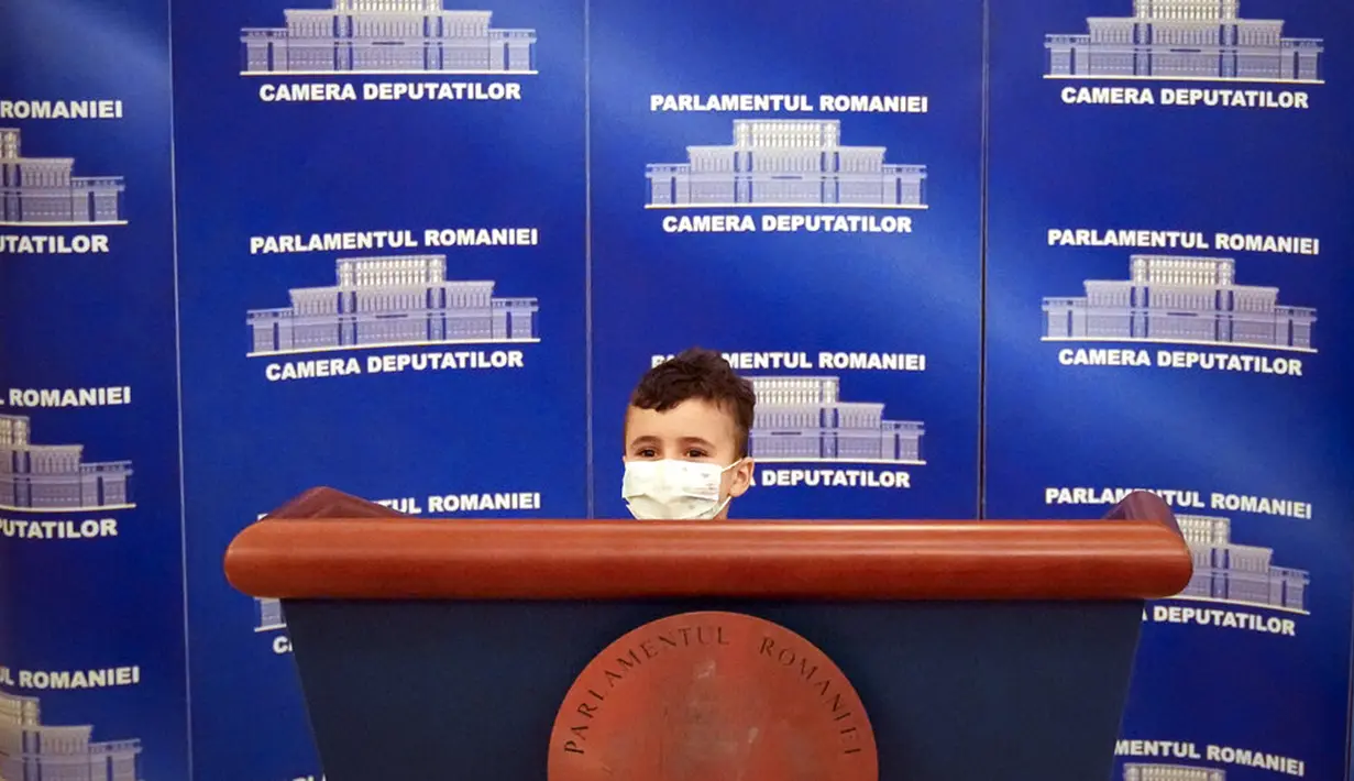 Seorang anak laki-laki berpose di belakang tribun pembicara di Istana Parlemen pada Hari Anak Internasional di Bucharest, Rumania, Selasa, Juni (1/6/2021). Istana Parlemen ini merupakan gedung administrasi terbesar kedua di dunia setelah Pentagon. (AP Photo/Vadim Ghirda)
