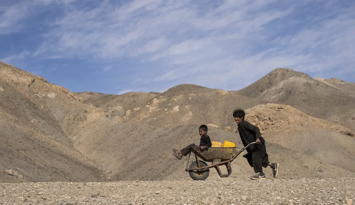 Seorang anak mendorong gerobak untuk mengambil air dari kolam yang tergenang, sekitar 3 km dari rumah di desa Kamar Kalagh, Herat pada 26 November 2021. Kekeringan Afghanistan, yang terburuk dalam beberapa dekade, kini memasuki tahun kedua, diperburuk oleh perubahan iklim. (AP/Petros Giannakouris)
