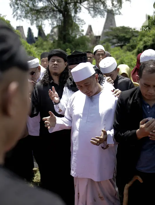 Penyanyi Opick berdoa di samping makam istri keduanya Wulan Mayasari di TPU Semper, Jakarta, Senin (19/3). Selama proses pemakaman ini, Opick didampingi oleh para santri dan kerabat dari perkumpulan komunitas bela diri. (Liputan6.com/Faizal Fanani)