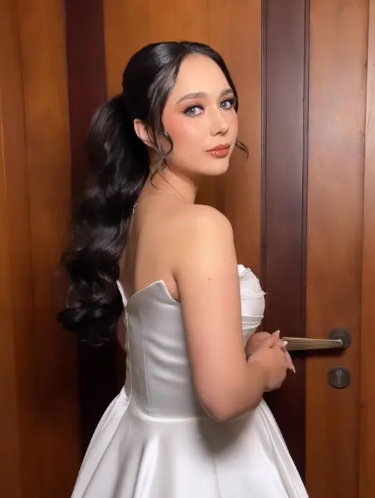 Sementara saat pemberkatan Raquel tampil dengan tatanan rambut sleek low bun, saat resepsi rambut Raquel ditata bergaya high ponytail curly memberi impresi fresh.  [@@loka.mata]