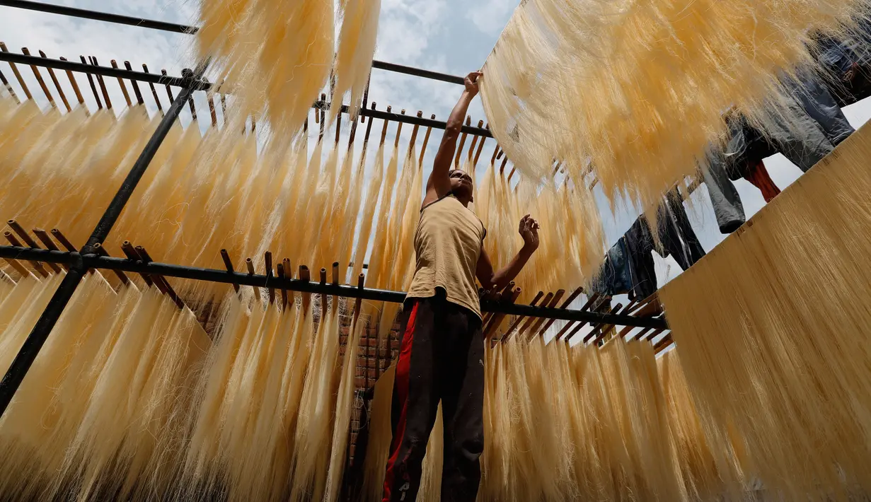 Seorang pekerja India menggantung helai bihun untuk dikeringkan di sebuah pabrik di Prayagraj, India pada 25 April 2020. Bihun diminati di kalangan Muslim ketika mereka berbuka puasa selama bulan suci Ramadan. (AP Photo/Rajesh Kumar Singh)