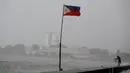 Bendera Filipina berkibar di dekat seorang warga yang memancing ditengah cuaca buruk akibat Topan Nepartak yang menerpa di Manila Bay, Filipina, Jumat (8/7). (REUTERS/Erik De Castro)