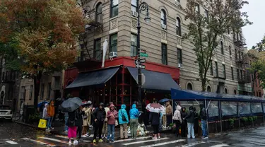 Orang-orang mengantre untuk memberikan penghormatan kepada aktor Matthew Perry di luar gedung apartemen yang digunakan sebagai pengambilan gambar eksterior dalam acara TV "Friends" di New York pada 29 Oktober 2023. (Adam GRAY / AFP)