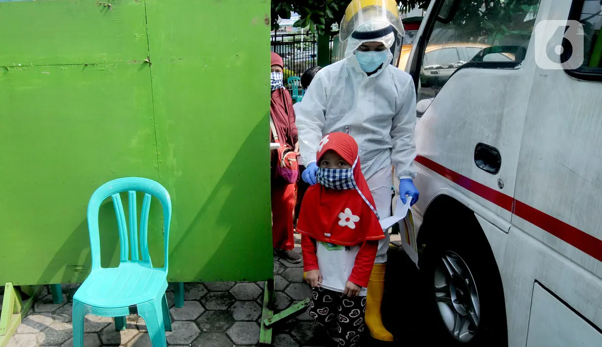 Paramedis membawa seorang anak saat testing PCR kepada warga yang pernah berhubungan dengan pasien positif COVID-19 di Puskesmas Cinere, Depok, Jawa Barat, Kamis (10/6/2021). Testing setelah tracing dilakukan kepada puluhan warga untuk meminimalisir penyebaran COVID-19. (merdeka.com/Arie Basuki)