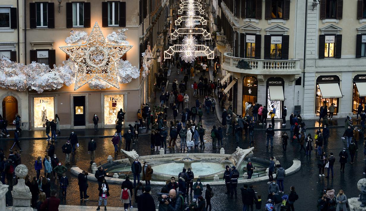 Pejalan kaki melintas di jalan perbelanjaan Roma, Italia pada Kamis (23/12/2021). Pemerintah Italia telah mewajibkan kembali penggunaan masker di luar ruangan untuk menahan peningkatan kasus Covid-19 yang didorong oleh varian Omicron. (Filippo MONTEFORTE/AFP)