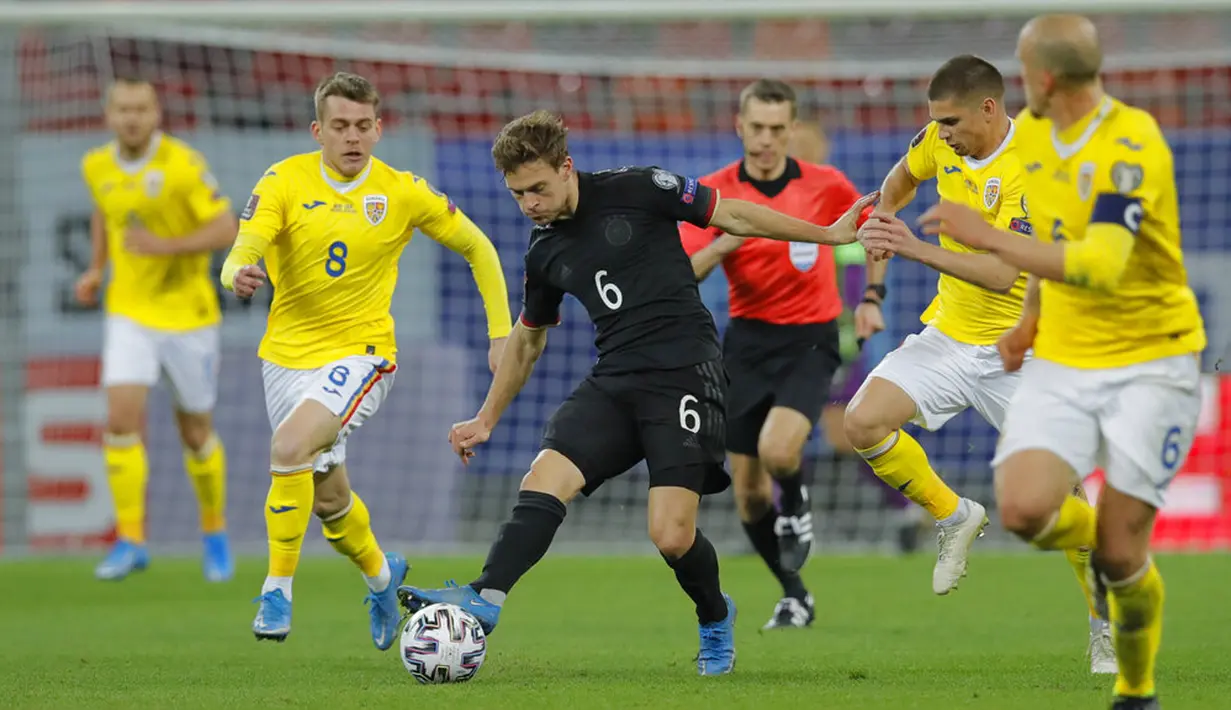 Pemain Jerman Joshua Kimmich (tengah) menembak bola di samping para pemain bertahan Rumania pada pertandingan Grup J kualifikasi Piala Dunia 2022 di Stadion National Arena, Bucharest, Rumania, Minggu (28/3/2021). Jerman menang 1-0 atas Rumania. (AP Photo/Vadim Ghirda)