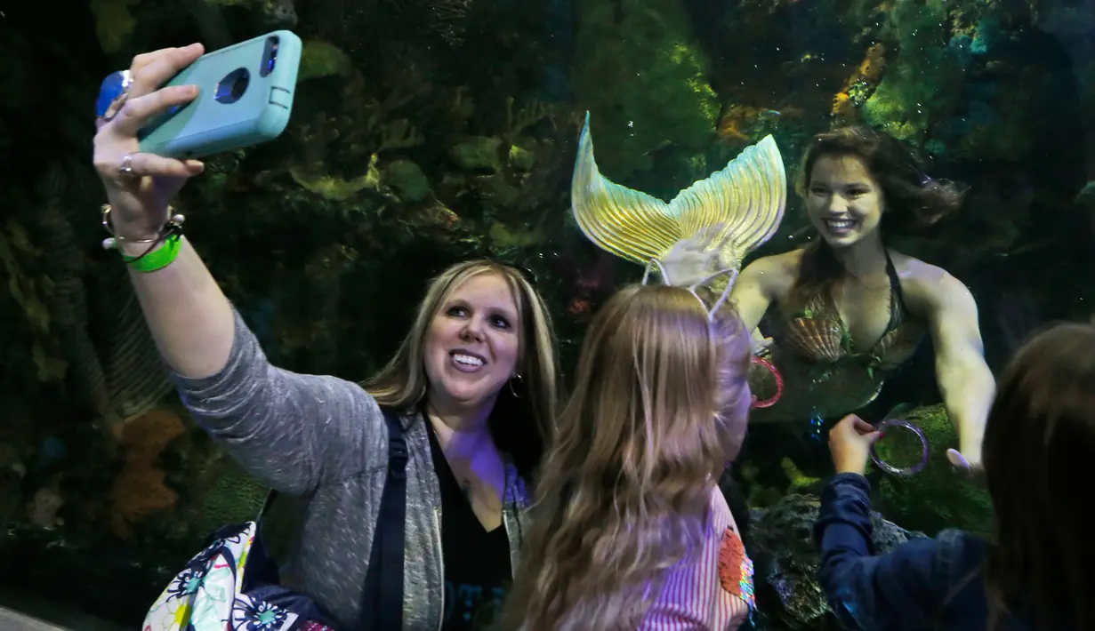 Seorang wanita berselfie dengan putri duyung Hales Parcels di Virginia Aquarium di Virginia Beach (3/4). (AP Photo/Steve Helber)