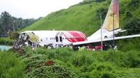 Petugas berdiri di atas puing-puing pesawat Air India Express yang tergelincir dari landasan pacu saat mendarat di Kozhikode, negara bagian Kerala, India, Sabtu, (8/8/2020). Akibat musibah tersebut sedikitnya 17 orang tewas. (AP Photo/C.K.Thanseer)