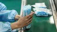 Pekerja memproduksi masker di sebuah pabrik di Yangzhou, Provinsi Jiangsu, China, Senin (27/1/2020). Masker tersebut diproduksi untuk mendukung pasokan bahan medis saat wabah virus corona melanda China. (STR/AFP)