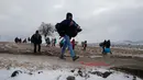 Sejumlah imigran berjalan melewati salju tebal membawa barang-barang mereka setelah melintasi perbatasan Makedonia, dekat desa Miratovac, Serbia, (18/1/2016). (REUTERS/Marko Djurica