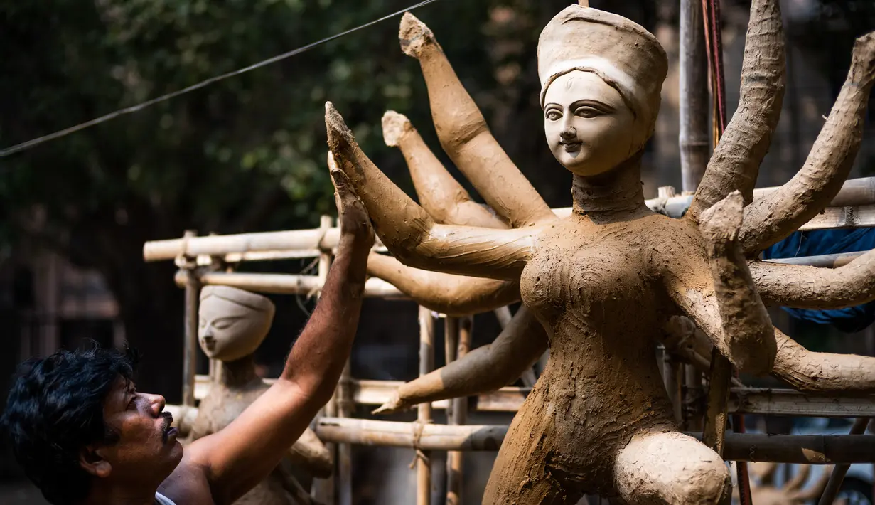 Seorang perajin membuat patung dewi Durga menjelang festival 'Durga Puja' di sebuah workshop di New Delhi, India, Rabu (14/10/2020). Durga Puja merupakan festival tahunan di Asia Selatan untuk memuja dewi Durga dari agama Hindu. (Photo by Jewel SAMAD / AFP)