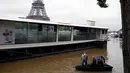 Warga berada di perahu di sungai Seine di dekat menara Eiffel, Paris, Prancis setelah hampir setiap hari hujan lebat menguyur negeri ini, (3/6). Banjir yang merendam sebagian wilayah Prancis Sejauh ini sudah dua orang tewas. (REUTERS/Pascal Rossignol)